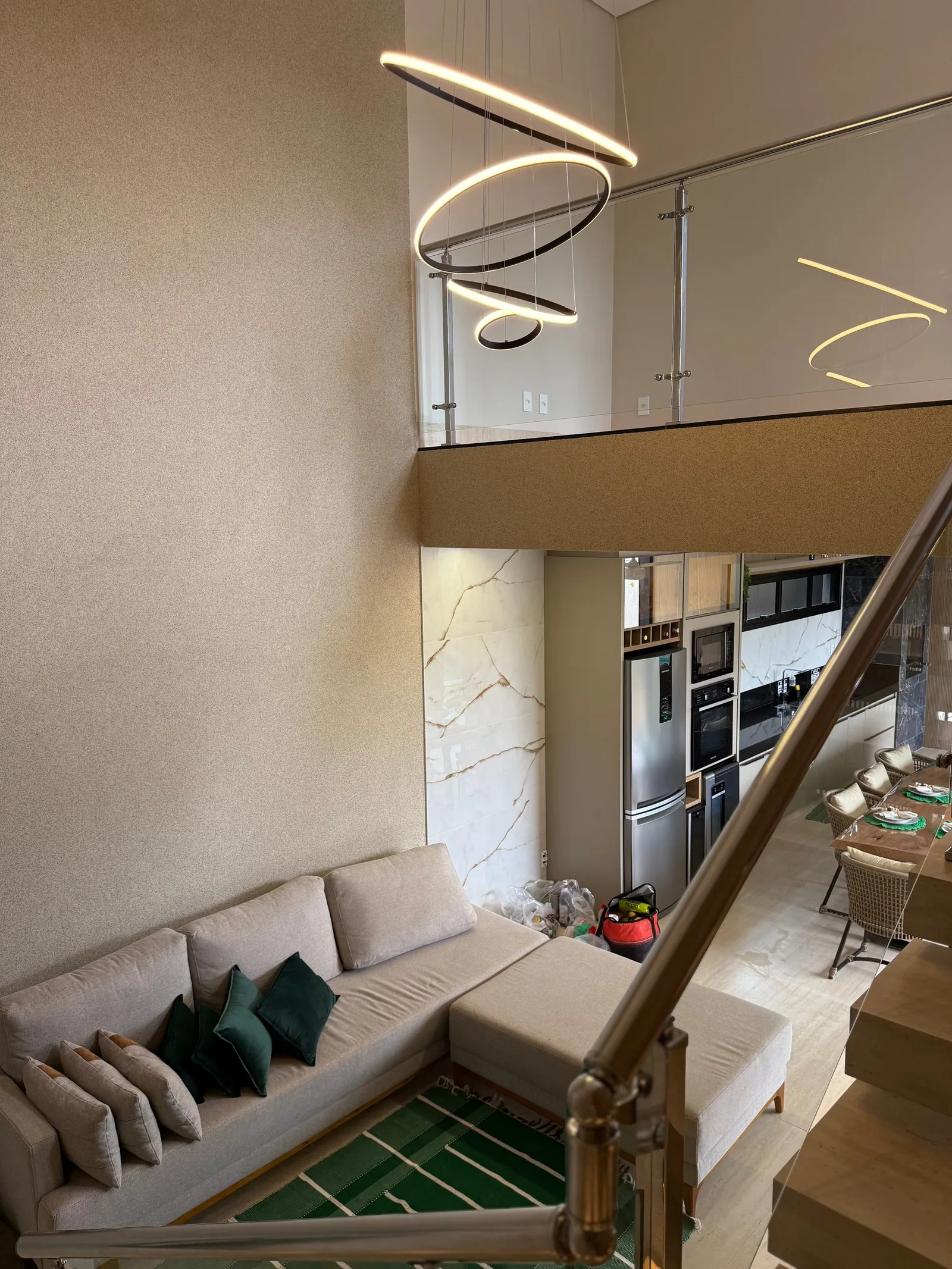 Escada flutuante com guarda-corpo de vidro, vista de cima para a cozinha