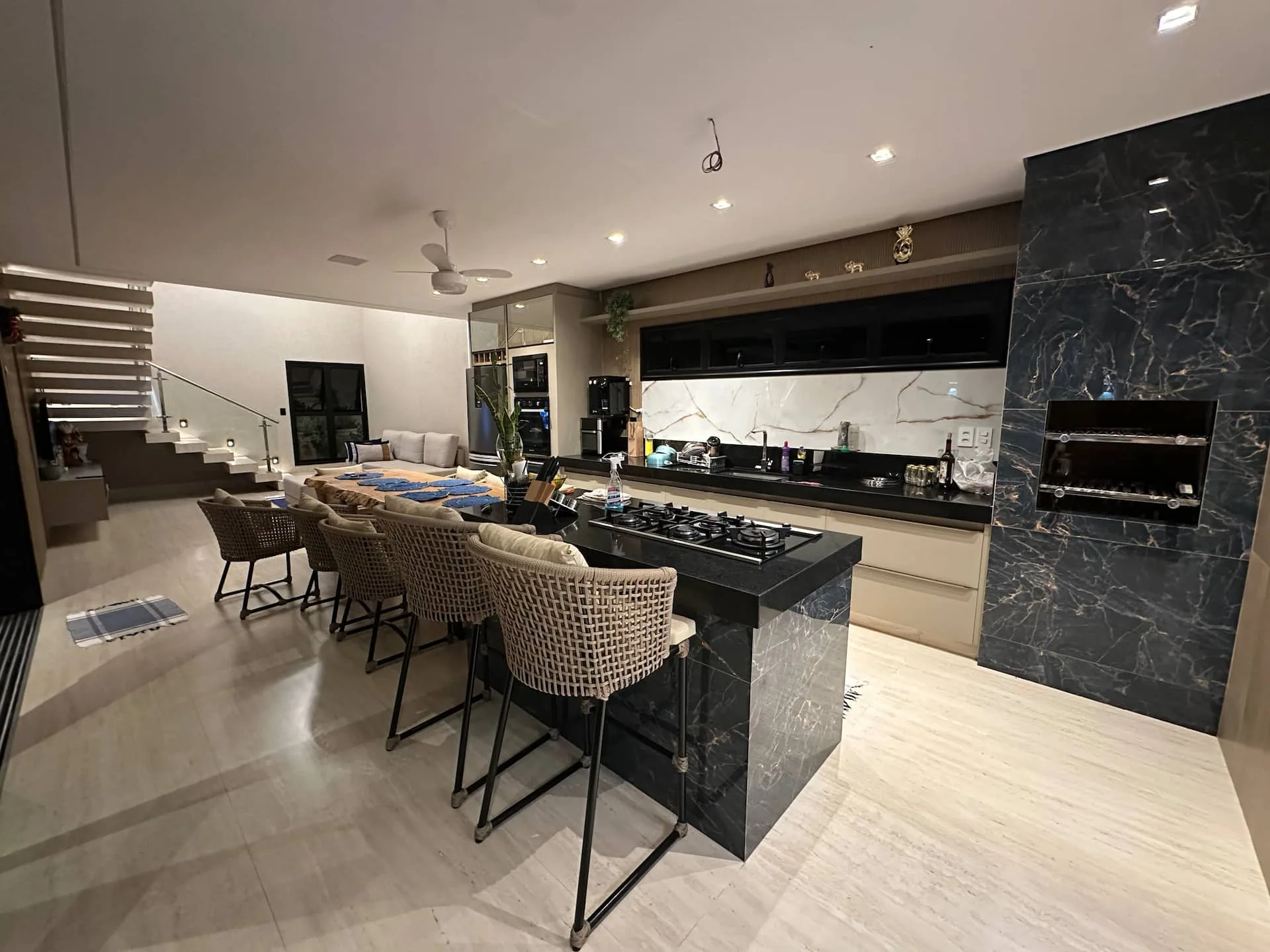 Cozinha em mármore preto veiado, ilha central com banquetas de fibra