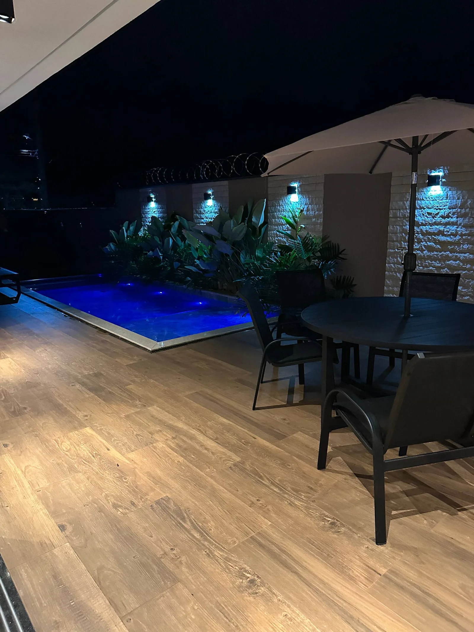 A fachada da casa à noite, piscina iluminada no térreo